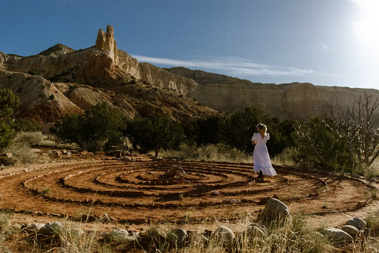 A woman in white dress walks through a desert