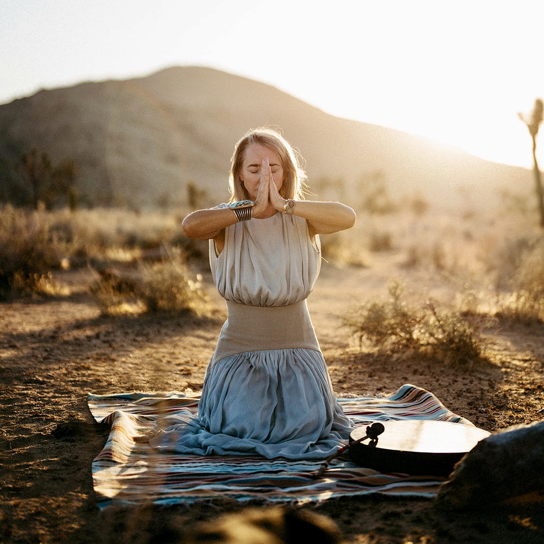 A woman in white dress walks through a desert