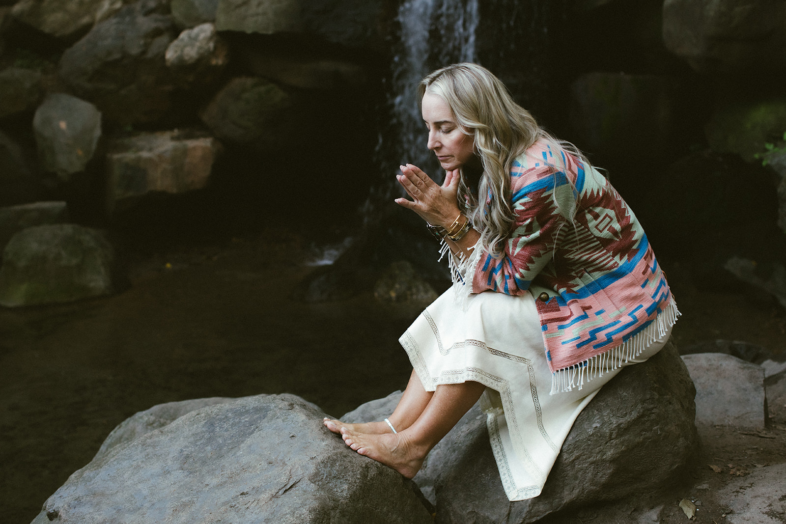 A woman in white dress walks through a desert