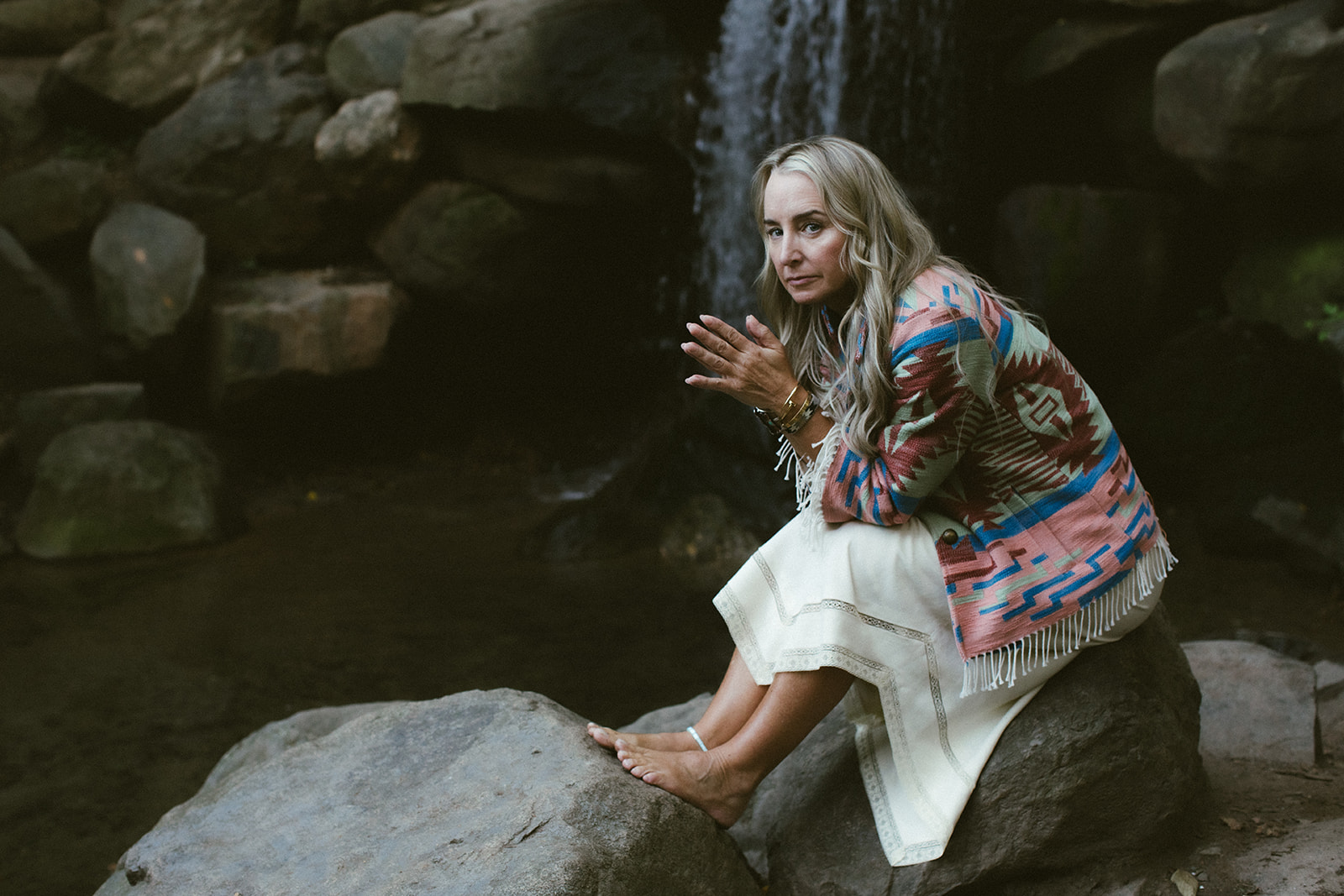 A woman in white dress walks through a desert